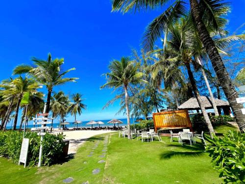 a resort with tables and chairs on the beach at Kosmos Apart Hotel Phu Quoc - Night market & Walkin to beach in Phú Quốc