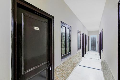 a hallway with a black door and some windows at OYO Flagship Hotel B K Palace in New Delhi