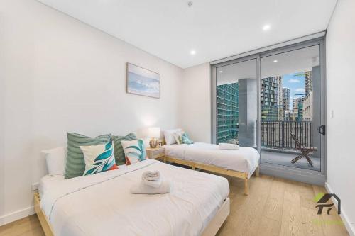 um quarto com 2 camas e uma grande janela em Vivid condo with Pool in Olympic Park em Sydney