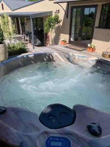 a hot tub filled with water in front of a house at Willow Cottage Retreat in Brightwater