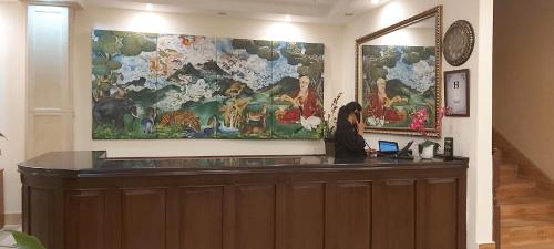 a hotel reception desk with a large painting on the wall at Hotel Kisa Thimphu in Thimphu