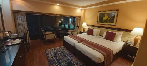 um quarto de hotel com uma cama grande e uma mesa em Hotel Kisa Thimphu em Thimphu