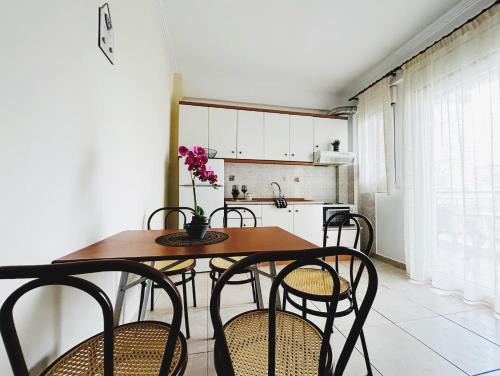 a kitchen with a wooden table and chairs and a kitchen with white cabinets at Hermanos in Flogita