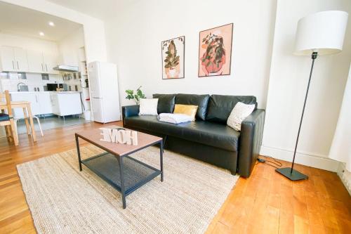 un salon avec un canapé noir et une table dans l'établissement #GP The Berri'Appart, à Grenoble