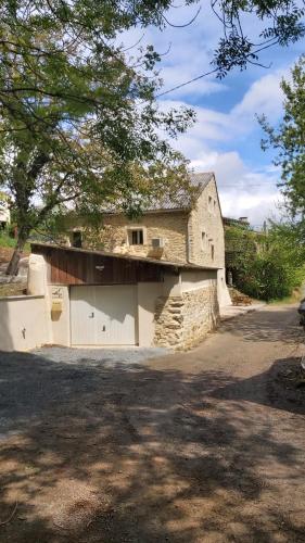 un gran edificio de piedra con un garaje delante de él en La Grange du Pradel, en Montredon-Labessonnié