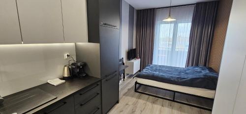 Habitación pequeña con cama y cocina en Villa Nova Apartamenty, en Olsztyn