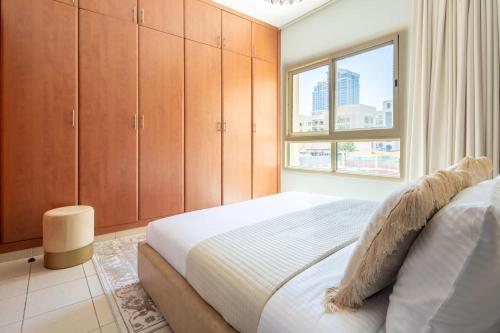 a bedroom with a bed with wooden cabinets and a window at Frank Porter - Al Dhafrah 2 in Dubai