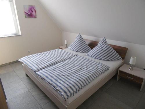 a bedroom with a bed with striped sheets and pillows at Just before the cape, holiday home B in Putgarten