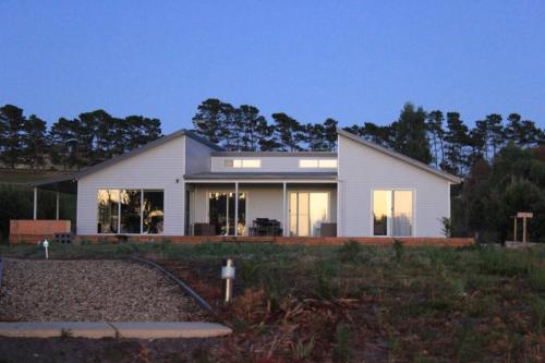 a large white house with windows on a field at Waterside living: the Tide House, Tasman Peninsula in Bream Creek