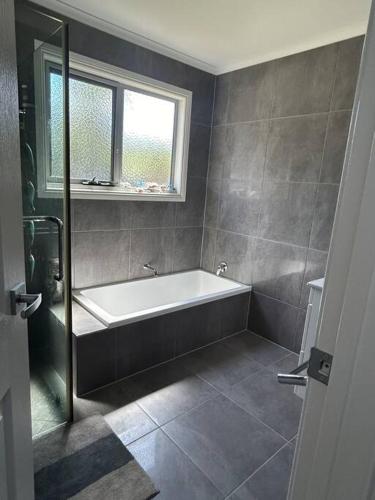 a bathroom with a bath tub and a window at Waterside living: the Tide House, Tasman Peninsula in Bream Creek