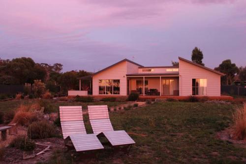 two white chairs sitting in front of a house at Waterside living: the Tide House, Tasman Peninsula in Bream Creek