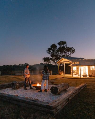 a man and a woman standing around a fire at Heartwood Farm Byron Bay Luxury Farm Stay in Federal