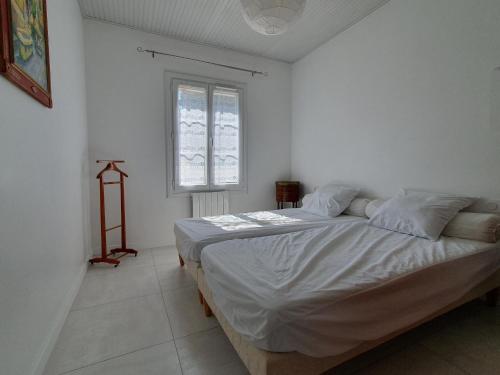 um quarto com uma cama grande com lençóis brancos e uma janela em Maison La Faute-sur-Mer, 3 pièces, 4 personnes - FR-1-476-187 em La Faute-sur-Mer