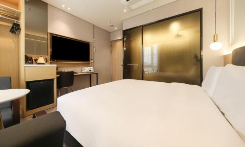 Busan Myeongji Ciel Ocean Hotel في بوسان: غرفة في الفندق مع سرير أبيض كبير ومكتب