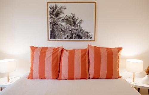 a bedroom with a bed with two orange and white pillows at Banksia Beach House in Port Fairy