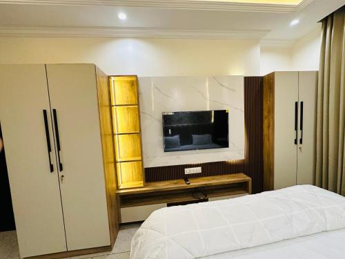 MG apartments في جودبور: غرفة نوم بسرير وتلفزيون بشاشة مسطحة