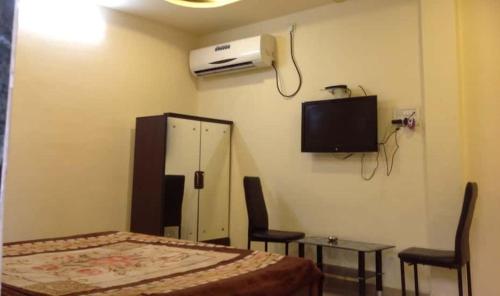 a bedroom with a bed and a tv and chairs at Hotel Galaxy in Rudraprayāg