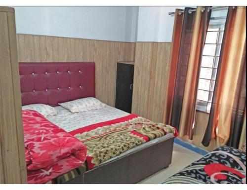 a bed with a red headboard in a room at Hotel Galaxy in Rudraprayāg