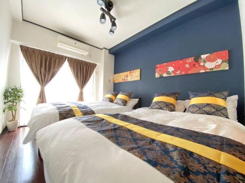 2 camas num quarto com uma parede azul em ファースト天王寺東501 em Osaka