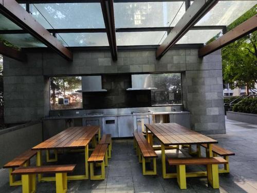 um pátio com 2 mesas de madeira e uma cozinha em 1Min to SouthernCross, Free,Tram,Pool,Gym,L606 em Melbourne