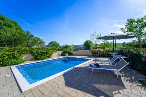 a swimming pool with an umbrella and a chair at Villa Mare With Private Pool And Garden - Happy Rentals in Malinska