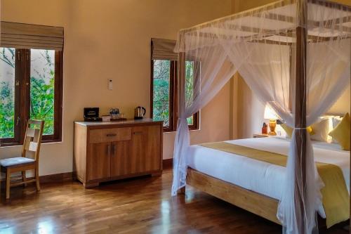 a bedroom with a canopy bed and a chair at Sigiriya Forest Edge By Marino Leisure in Sigiriya