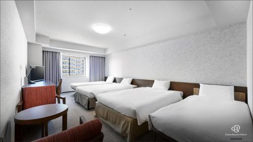 a hotel room with two beds and a television at Daiwa Roynet Hotel Naha Omoromachi in Naha