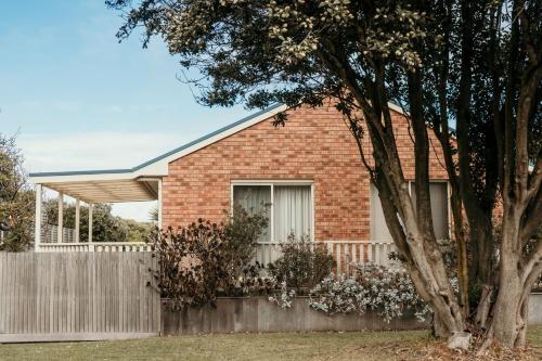 a brick house with a wooden fence at Banksia Beach House in Port Fairy