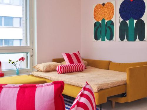 a room with a couch and a bed with pillows at Candy-Colored Two-Room Condo with Sweet views in Helsinki