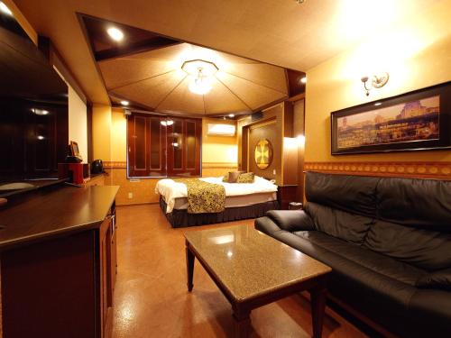 a living room with a couch and a bed in a room at ホテル カーシュ Cache 男塾ホテルグループ in Himeji