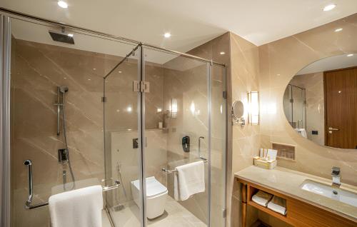 a bathroom with a shower and a toilet and a sink at Gift City Club, a member of Radisson Individuals in Gandhinagar