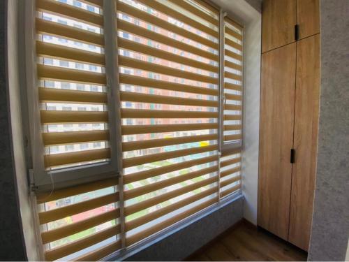 ein Fenster mit Holzjalousien in einem Zimmer in der Unterkunft Уютные апартаменты в элитном комплексе in Almaty
