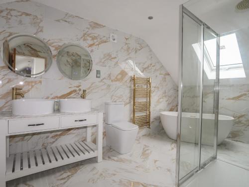 a bathroom with two sinks and a toilet and a tub at Blue Bay Villa in Holyhead