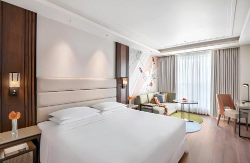 a bedroom with a white bed and a living room at Hyatt Centric Rajpur Road Dehradun in Dehradun
