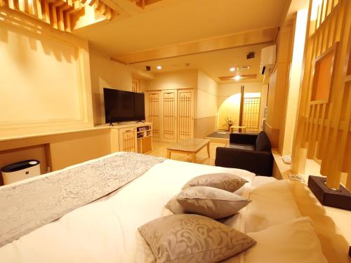 1 dormitorio con 1 cama blanca grande y 3 almohadas en ホテル カーシュ Cache 男塾ホテルグループ en Himeji