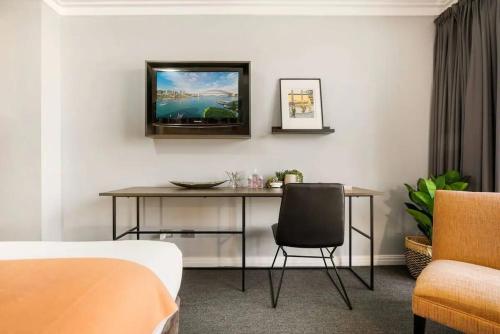 a room with a table and a tv on a wall at KozyGuru | Sydney CBD | Haymarket 2 Bed Studio in Sydney