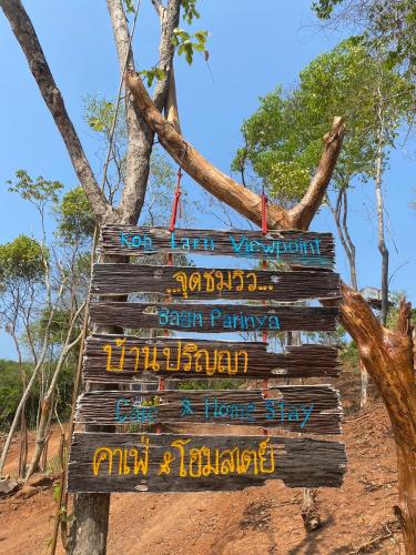 a wooden sign hanging from a tree in a field at Parinya Hill Homestay & Cafe Koh Larn in Ko Larn