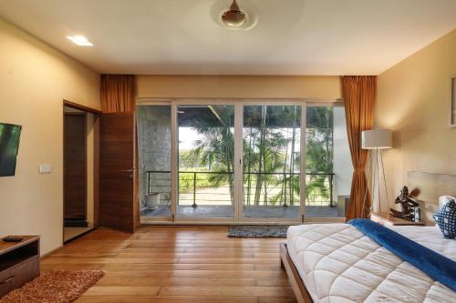 1 dormitorio con cama y ventana grande en JalMahal by JadeCaps Bay View & Pool Dabolim en Vāsco Da Gāma