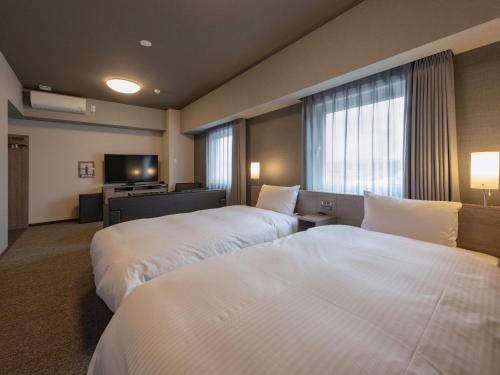a hotel room with two beds and a window at Hotel Route Inn Owariseto Ekimae in Seto