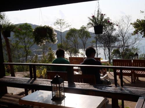 two people sitting on a bench looking out at the mountains at Parinya Hill Homestay & Cafe Koh Larn in Ko Larn