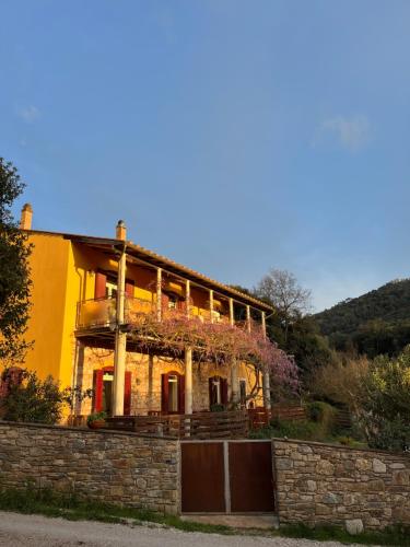 a yellow house with a stone wall in front of it at B&B La Fucinaia Pet Friendly Adults only in Campiglia Marittima