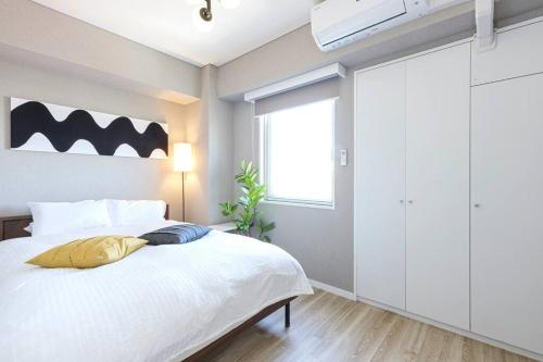 a bedroom with a white bed and a window at ホステルアミーチ Hostel Amici in Tokyo