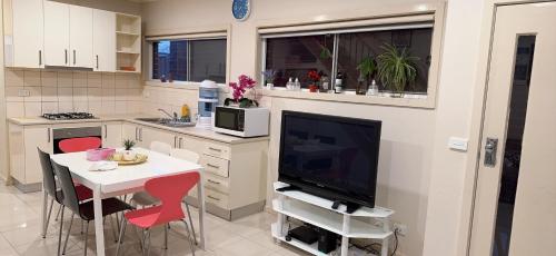 cocina con TV y mesa con sillas en 3 bedroom townhouse in Local shopping mall, en Melbourne