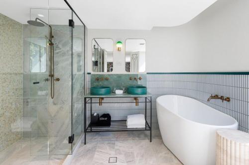 La salle de bains est pourvue d'une baignoire et d'une douche en verre. dans l'établissement 202 Elizabeth Hotel - The Oxford - Australia, à Sydney