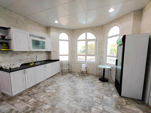 uma cozinha com armários brancos e um frigorífico preto em Mountains resort by escape time em Fujairah