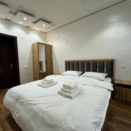 1 dormitorio con 1 cama blanca grande y toallas. en Cozy Hostel, en Yunusobod