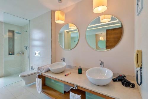 a bathroom with two sinks and two mirrors at StayVista at Acacia Skies with Beach View & Kitchen Access in Vasco Da Gama
