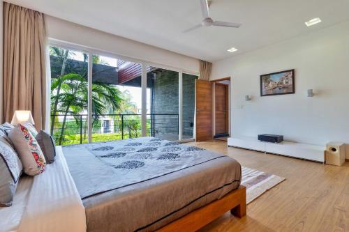 瓦斯科達伽馬的住宿－StayVista at Acacia Skies with Beach View & Kitchen Access，一间卧室设有一张大床和一个大窗户