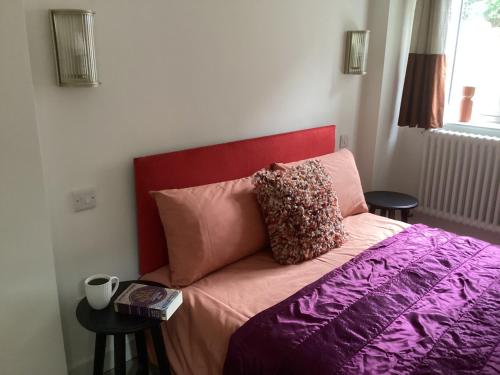 a bed with a red headboard and pillows on it at Forest Heath Holidays - The Nook in Ringwood