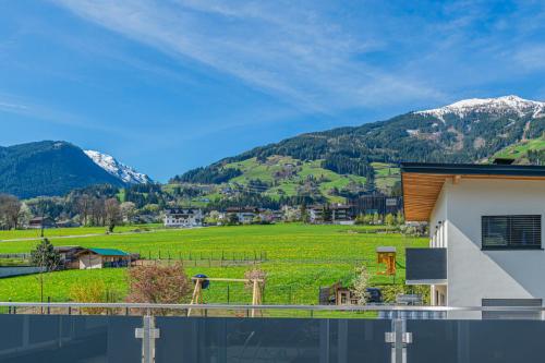 a house with a view of a field and mountains at H19 - Modernes Ferienhaus 145qm, 3SZ, Wellnessbereich mit Sauna und Dachterrasse mit Panoramablick, Kühlen und Heizen mit Geothermie in Fügen